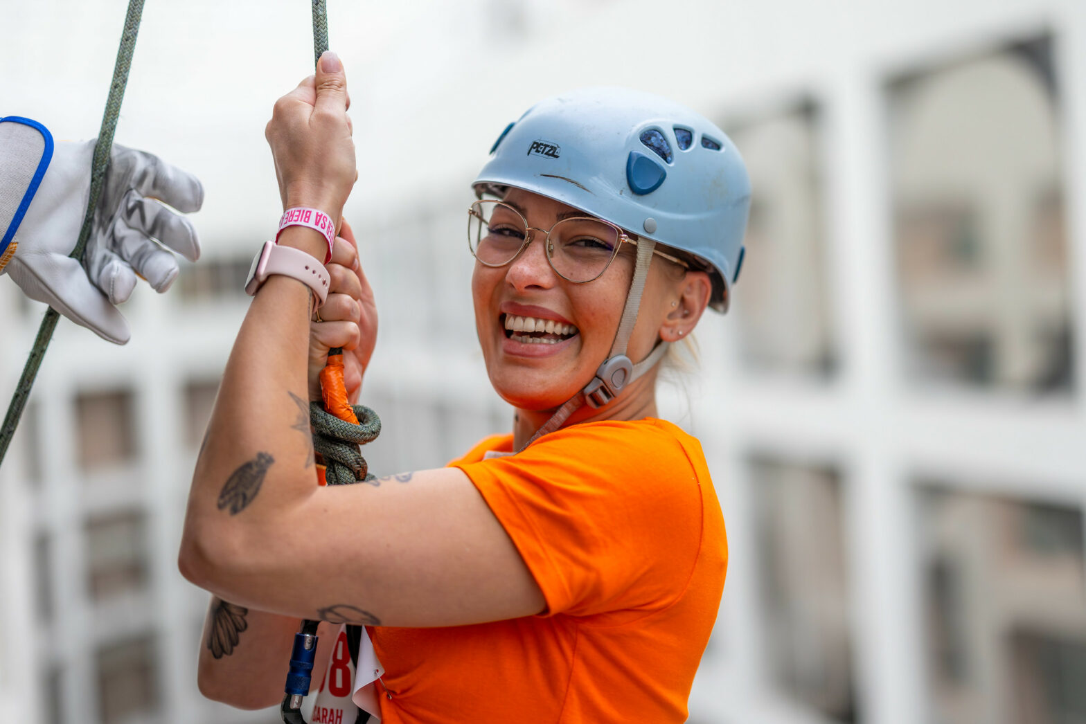 Femme qui sourit avant une descente en rappel, une activité originale lors d'un team building