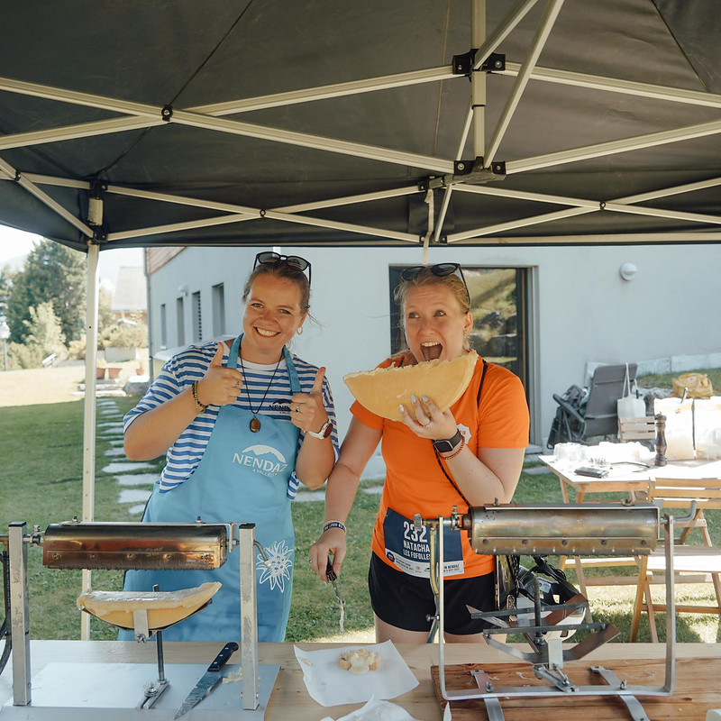 Femme qui s'apprête à croquer dans une demi raclette lors d'un week-end entre filles à la montagne