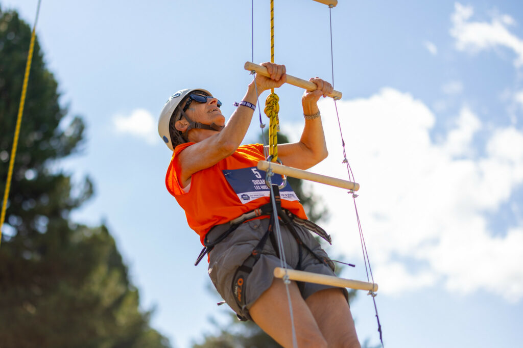 Femme qui fait de l'échelle de corde pour monter à un télésiège lors d'un week-end à la montagne entre filles